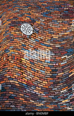 Warped image of cast iron utility handhole in colorful brick paved street at Ybor City area of Tampa, Florida Stock Photo