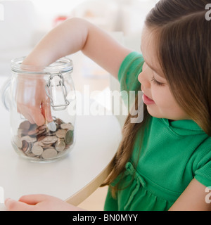 Mixed race girl taking coin out of jar