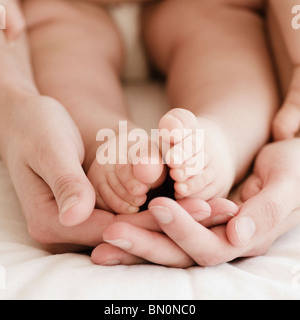 Mother holding mixed race baby boy's feet Stock Photo