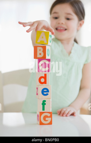 Mixed race girl stacking alphabet blocks Stock Photo