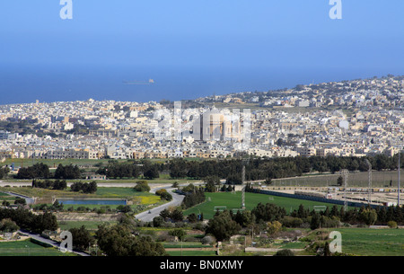 A view of the Rotunda or domed chuch, Mosta, Malta taken from Mdina. In the distance is the Mediterranean Sea with cargo ships. Stock Photo