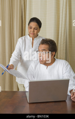 Man looking shocked at a bill held by a woman Stock Photo