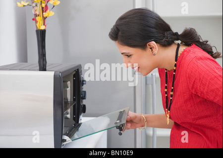 Woman opening a microwave oven in the kitchen Stock Photo
