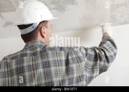 Construction worker in white hardhat plastering the ceiling Stock Photo