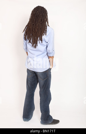 Young man with dreadlocks standing, hands in pockets back to camera Stock Photo