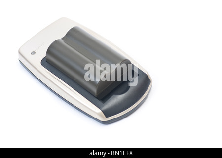 A small camera battery on its charger, isolated on white. Stock Photo