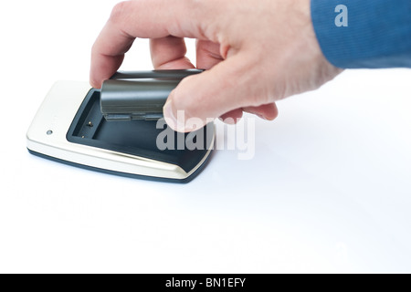 A hand grabbing a charged camera battery from a small charger, isolated on white. Stock Photo