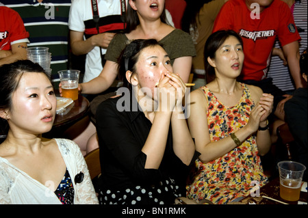 A worried South Korean football supporter watching her team play against Uruguay in a London Pub during the 2010 World Cup Stock Photo