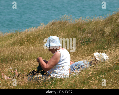 Old couple sat in the long grass, Padstow, UK Stock Photo