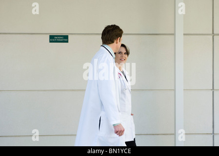 Doctors chatting and walking together along hospital corridor Stock Photo