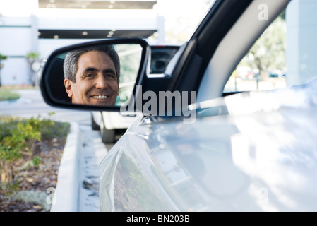 Man sitting in parked car, reflection in side-view mirror Stock Photo