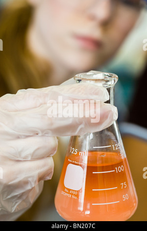 Researcher holding beaker filled with chemicals Stock Photo