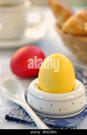 Yellow Easter Egg in an Eggholder, Red Egg lying at the Side Stock Photo