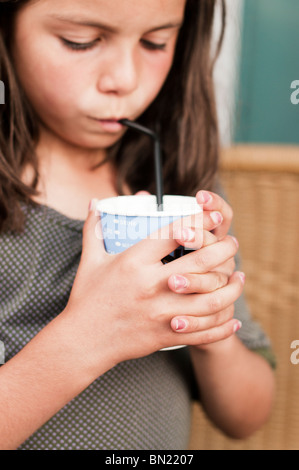 Child drinking with a straw from a paper cup Stock Photo