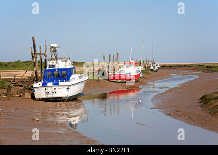 Boats beached at low tide in a tidal creek at Thornham, Norfolk, England United Kingdom. Stock Photo