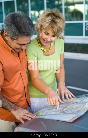 Mature couple looking at road map together, discussing route for road trip Stock Photo