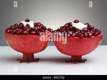 Two cut Pomegranates filled with juicy seeds and topped with Yogurt Stock Photo