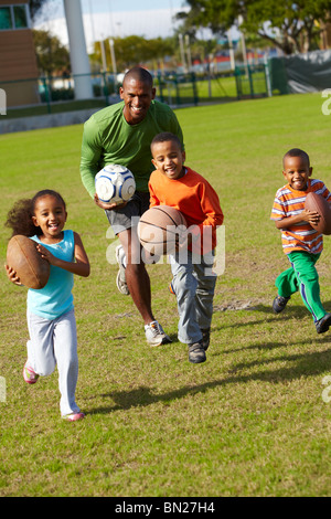 African American father playing ball with children Stock Photo