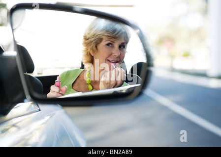 Woman putting on makeup, reflection in side-view mirror Stock Photo
