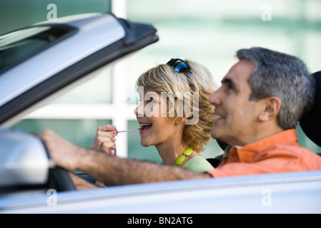 Mature couple in car together, woman putting on lip gloss Stock Photo