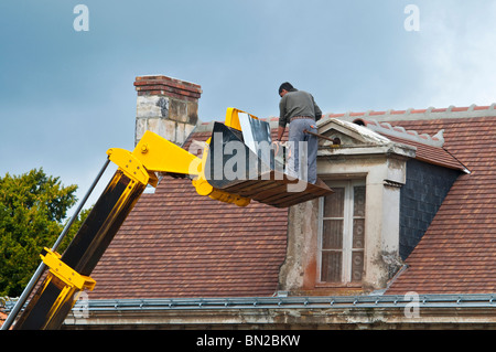Contractor repairing attic dormer roof / no safety equipment or helmet - France. Stock Photo