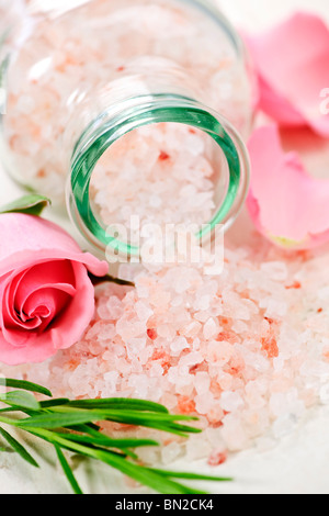 Pink bath salts in a glass jar with flowers and herbs Stock Photo