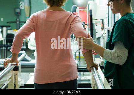 Patient undergoing rehabilitation walking exercises with assistance from physical therapist Stock Photo