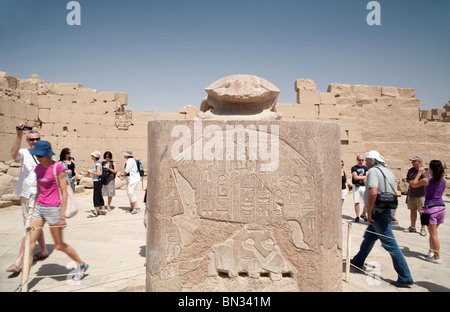 Tourists walking around the stone statue of the scarab beetle for good luck, Karnak temple, Luxor Egypt Stock Photo