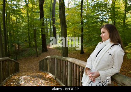 Young woman standing on bridge in forest Stock Photo