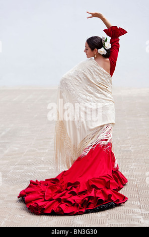 Woman traditional Spanish Flamenco dancer dancing outside in a red dress with a cream colored shawl Stock Photo