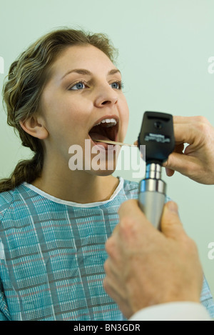 doctor using a tongue depressor to examine a sore throat with severe ...