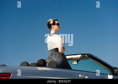 Young woman standing up in convertible looking at view Stock Photo