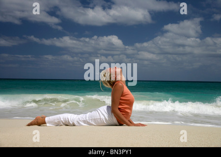 Woman practising yoga on a beach, side view Stock Photo