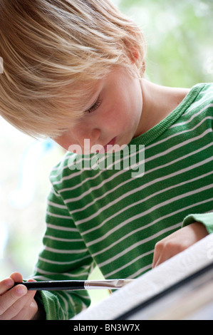 Young boy painting, low angle view Stock Photo