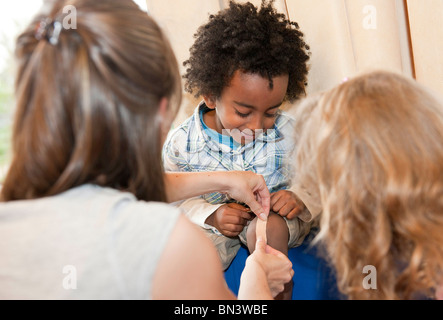 Kindergarten teacher applying a plaster on boys leg Stock Photo