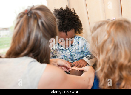 Kindergarten teacher applying a plaster on boys leg Stock Photo