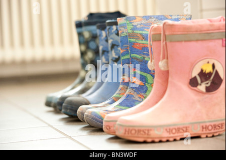 Rubber boots in a row on a tiled floor Stock Photo