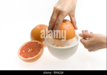 pink grapefruit being squeezed by hand Stock Photo