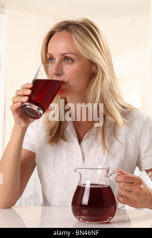 WOMAN DRINKING POMEGRANATE JUICE Stock Photo