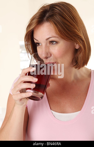 WOMAN DRINKING POMEGRANATE JUICE Stock Photo
