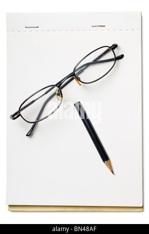 a pair of reading glasses and black pencil on a blank pad Stock Photo