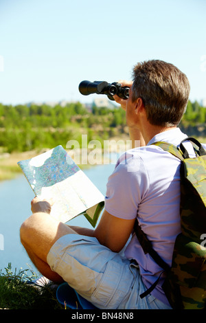 Back view of male tourist looking through binoculars in the country Stock Photo
