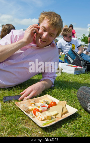 Man with plate of salad relaxing in the sunshine talking on his mobile phone at Hay Festival 2010 Hay on Wye Powys Wales UK Stock Photo