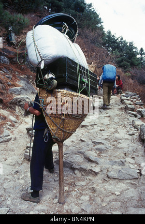 Porter with his load approaches Namche Bazar; Solo Khumbu district; Everest region; Nepal Stock Photo