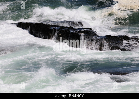 Atlantic Ocean with waves crashing over black rocks Hermanus western Cape South Africa Stock Photo