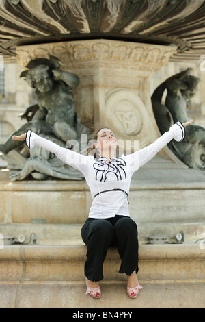beautiful busines woman sitting on stone fountain edge breathing and happy Stock Photo