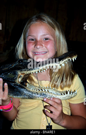 Young pretty smiling blond freckle faced Louisiana girl holding dried Alligator mississippiensis head in Grand Chenier LA Stock Photo