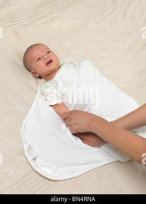 Mother swaddling a six week old baby boy Stock Photo
