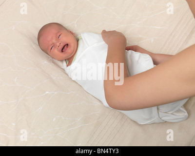 Mother swaddling a crying six week old baby boy