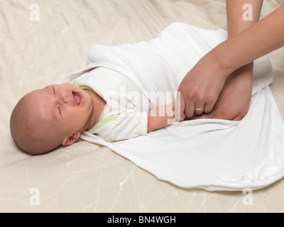 Mother swaddling a crying six week old baby boy